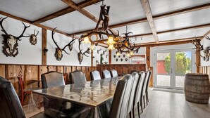 A restaurant with a long wooden table, leather chairs, and a chandelier made from antlers.