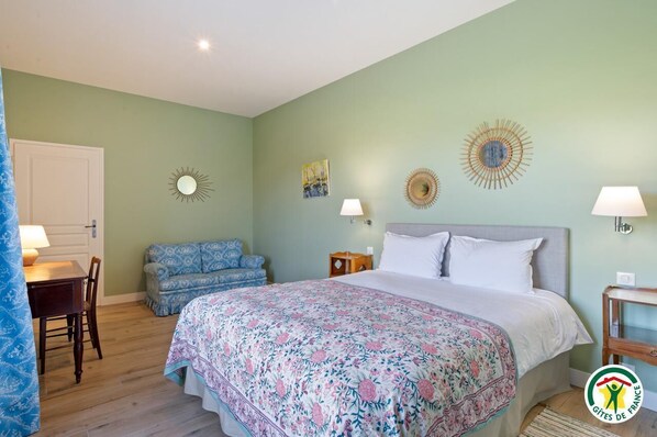 A bedroom with a bed, a desk, and a chair. There are wall decorations and a window.