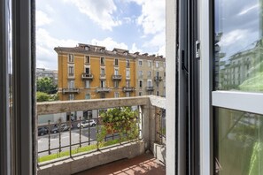 A balcony with a view of a yellow building, a railing, and a potted plant. - GIACOSA, 71 – Spacious apartment for 6 (Milano)