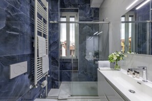 Ein modernes Badezimmer mit einer Duschkabine aus Glas, einem weißen Waschbecken und einem Spiegel.
