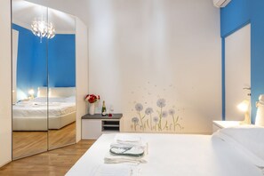 A bedroom with a mirrored wardrobe, a bedside table with a bottle and glasses, and a wall with floral decals. - GIACOSA, 71 – Spacious apartment for 6 (Milano)