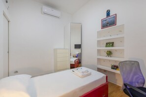 A bedroom with a bed, a dresser, a mirror, a chair, and a shelf with books and a globe. - GIACOSA, 71 – Spacious apartment for 6 (Milano)