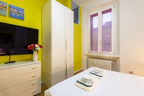 A room with a bed, a white dresser, a mirror, a window with curtains, and a vase with flowers. - GIACOSA, 71 – Spacious apartment for 6 (Milano)