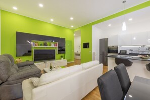 A modern living room with a flat-screen TV, a sofa, and a dining area with a table and chairs. - GIACOSA, 71 – Spacious apartment for 6 (Milano)