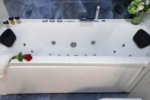 A white bathtub with multiple jets, a rose, and toiletries on the side. - GIACOSA, 71 – Spacious apartment for 6 (Milano)