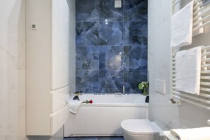 A bathroom with a bathtub, toilet, and a towel rack. - GIACOSA, 71 – Spacious apartment for 6 (Milano)
