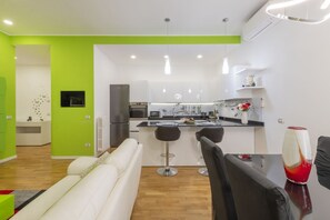 A modern kitchen with white cabinets, a central island with stools, and a dining area with a table and chairs. - GIACOSA, 71 – Spacious apartment for 6 (Milano)