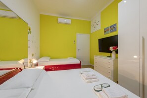 A hotel room with two beds, a TV, a dresser, and a door.