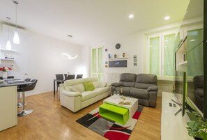 A modern living room with a white sofa, a green coffee table, a grey sofa, a dining area with a white table, and a TV on a white stand. - GIACOSA, 71 – Spacious apartment for 6 (Milano)