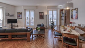 Una sala de estar moderna con sofá, una mesa de centro, televisor y un comedor con mesa y sillas.