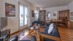 Un salón amplio con sofá, una mesa de centro y televisor. Hay un comedor con mesa y sillas.
