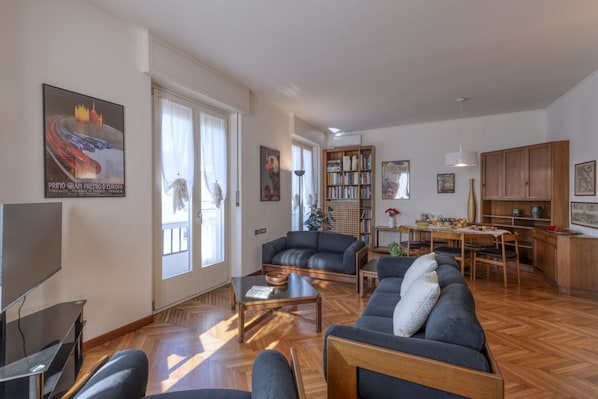 Un salon spacieux comprenant un canapé, une table basse et un téléviseur. Il y a également un coin repas avec une table et des chaises.