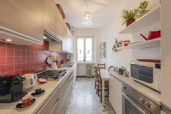 A modern kitchen with a gas stove, microwave, and a dining area with a table and chairs.