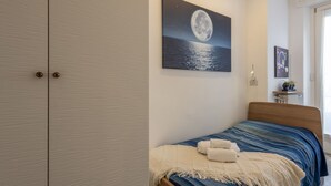 A bedroom with a bed, a night sky painting, a wardrobe, and a nightstand with a lamp. - Otto Novembre, 3 – Spacious and Elegant with a View (Milano)