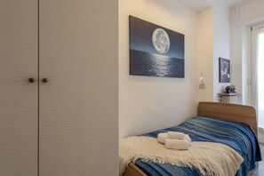 A bedroom with a bed, a night sky painting, a wardrobe, and a nightstand with a lamp. - Otto Novembre, 3 – Spacious and Elegant with a View (Milano)