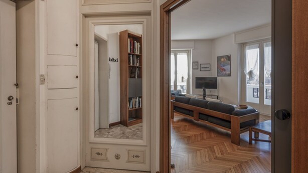 Un pasillo que conduce a una sala de estar con un sofá, una estantería y un televisor.