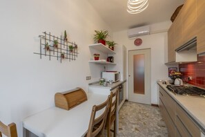 A compact kitchen with a dining area, a wall-mounted plant grid, a microwave, and a stove. - Otto Novembre, 3 – Spacious and Elegant with a View (Milano)