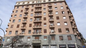 Un edificio de varios pisos con balcones, locales comerciales y una entrada visible.