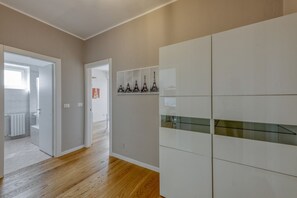 Een gang met een houten vloer, witte wanden en een spatwand van glazen tegels.