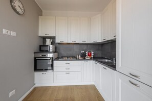 A compact kitchen with white cabinets, a microwave, an oven, and a coffee maker.