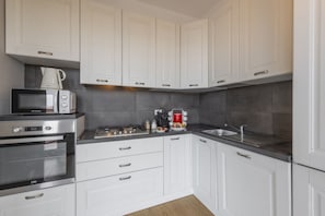 A modern kitchen with white cabinets, a microwave, an oven, and a sink. - Omodeo, 19 – Spacious and Panoramic (Milano)