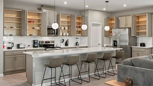 A modern kitchen with an island, bar stools, and built-in shelves. - Family escape: pool, hot tub & resort access (Kissimmee)