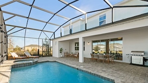A modern indoor pool area with a glass ceiling, lounge chairs, and a barbecue grill. - Family escape: pool, hot tub & resort access (Kissimmee)