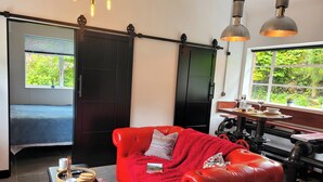 A modern living room with a red leather sofa, a black sliding door, and a dining area with a table and chairs.
