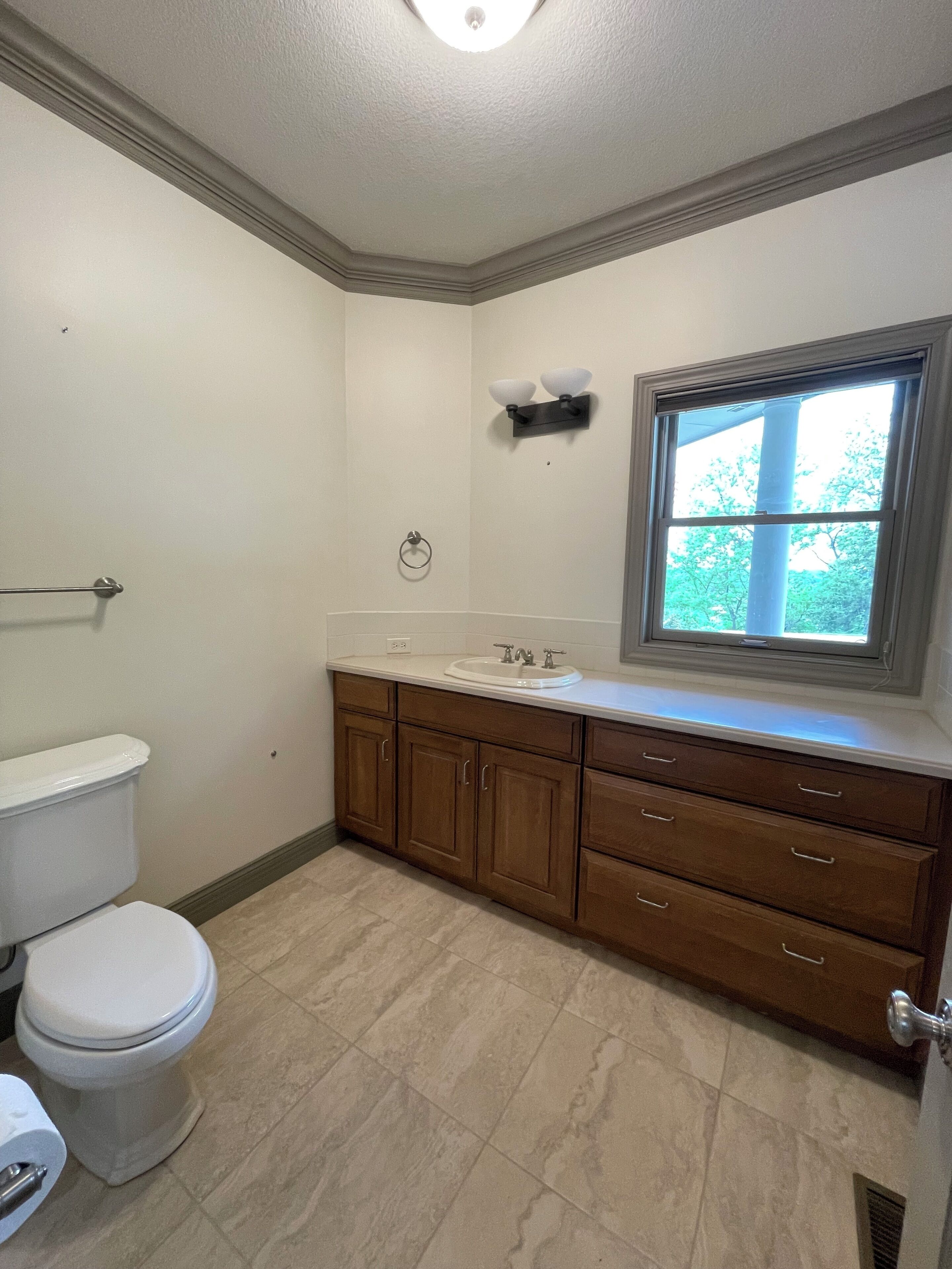 Une salle de bain comprenant des toilettes, un lavabo, un meuble-lavabo et une fenêtre.