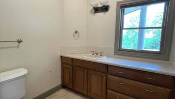 Une salle de bain comprenant des toilettes, un lavabo, un meuble-lavabo et une fenêtre.