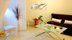 Un soggiorno moderno con un tavolino in vetro, un divano rosso scuro, una panca bianca e un vaso decorativo con piante essiccate.