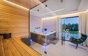 Relax in a serene bathroom with a glass-enclosed hot tub and garden views.