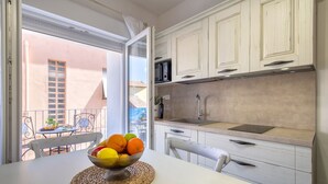 Una cocina con armarios blancos, un lavamanos de acero inoxidable y una zona de comedor con una mesa y sillas.