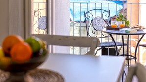 Un balcón con una mesa, sillas y un frutero.
