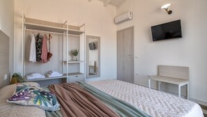 Une chambre à coucher comprenant un lit, une armoire, un téléviseur et un banc.