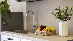 Une cuisine équipée d’un évier encastré, d’un panier de fruits et d’une plante en pot.