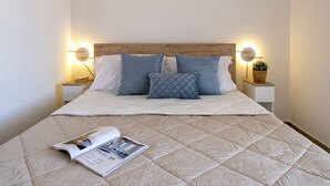 Ein ordentlich bezogenes Bett mit einer gesteppten Decke, zwei Nachttischen mit Lampen und einer Zeitschrift auf dem Bett.