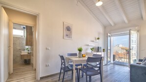 Eine moderne Küche mit Essbereich, Meerblick und einem Balkon mit Gartenmöbeln.