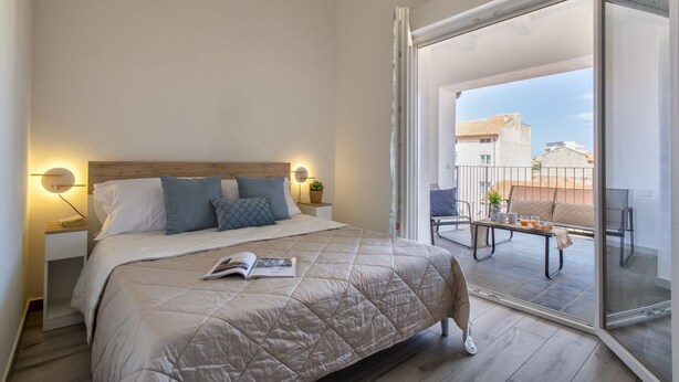 Ein Schlafzimmer mit Bett, Nachttischen, einer Leselampe und einem Balkon mit Tisch und Stühlen.