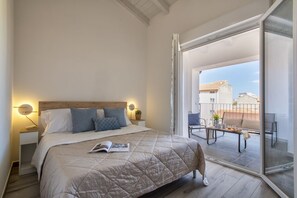A bedroom with a bed, bedside tables, a reading lamp, and a balcony with a table and chairs. - Casa Asfodelo. Apartment a few steps from the historic center. (Olbia)