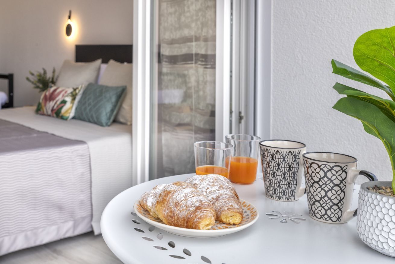 A neatly arranged breakfast table with a croissant, two glasses of orange juice, and patterned mugs.