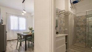 Una cocina moderna con comedor, una pared blanca y un box de ducha con diseño.