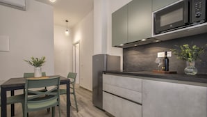 Una cocina moderna con armarios grises, microondas integrado y una zona de comedor con mesa y sillas.