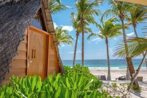 Puerta de madera, palmeras y vista a la playa.
