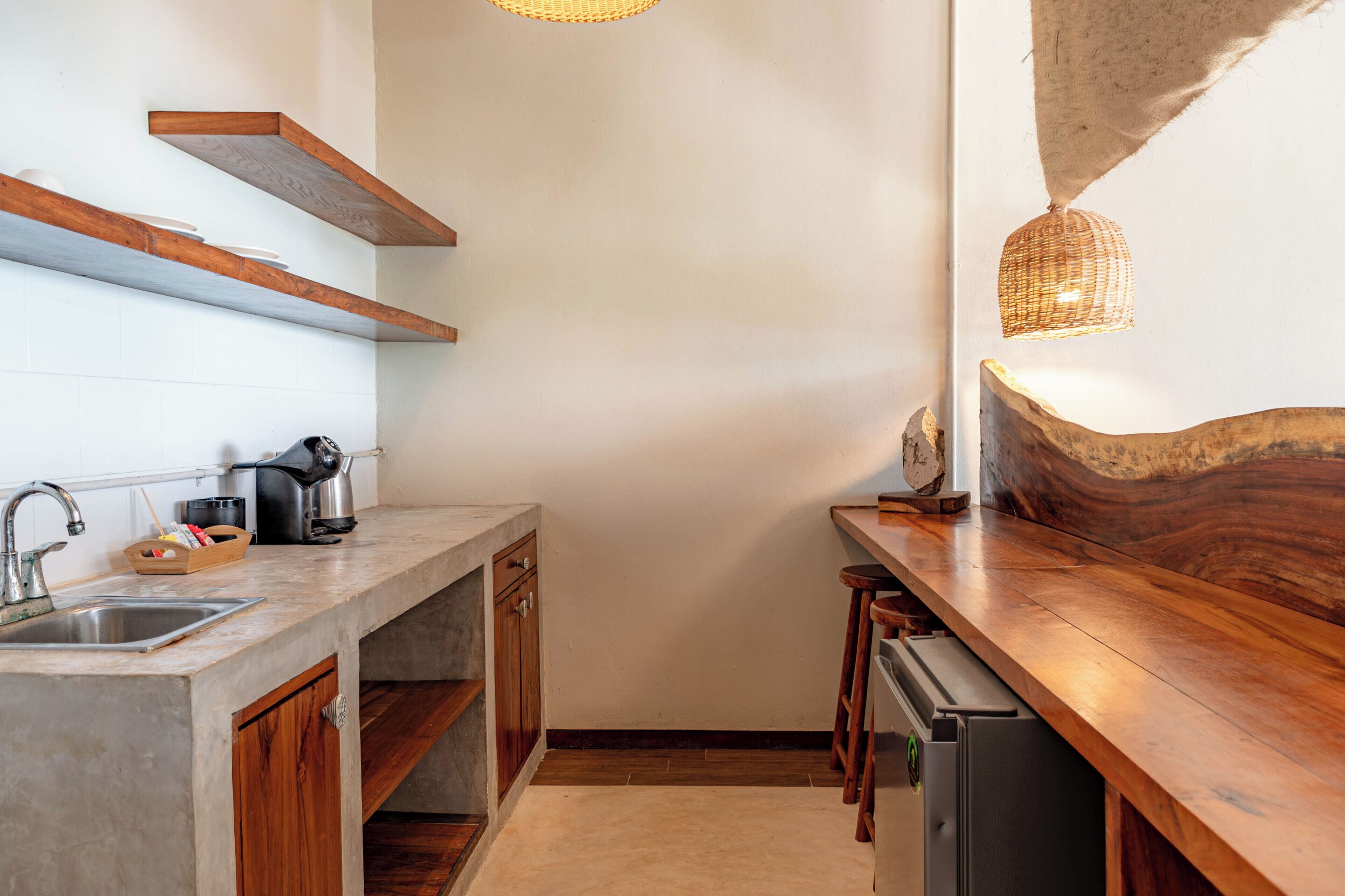 A kitchen with a wooden countertop, a built-in dishwasher, and a hanging light fixture.
