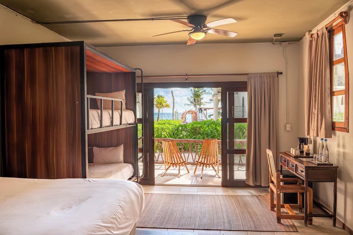 A room with a bed, a desk, a chair, a ceiling fan, and a view of the outdoors.