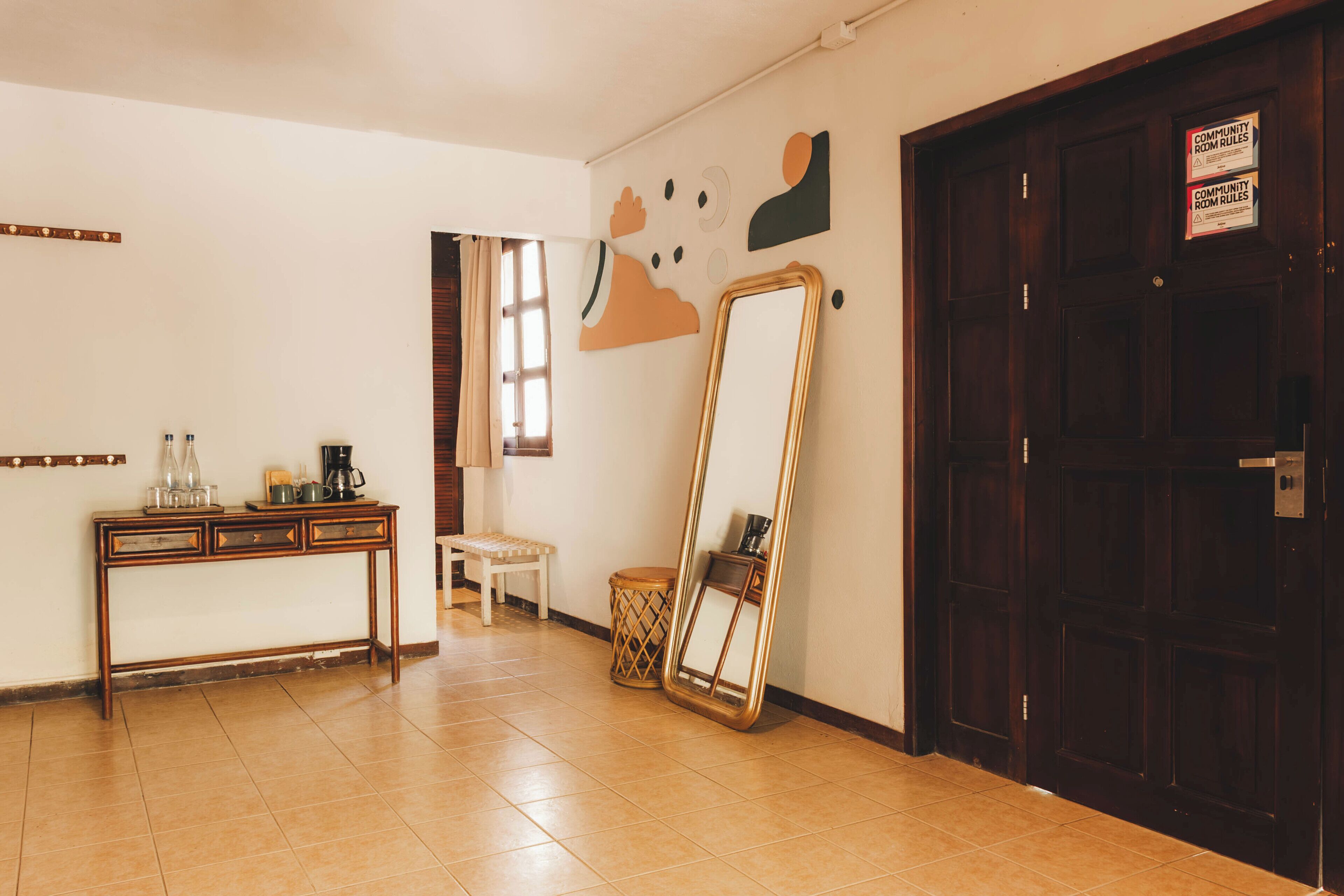 A room with a wooden table, a bench, a large mirror, and a door with a sign.