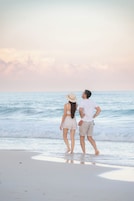 Una pareja parada en la playa mirando al océano.