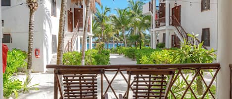 Un resort con una cabaña de techo de paja, palmeras y un sendero que lleva a una piscina.