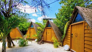 A row of wooden cabins with thatched roofs, numbered 5 and 6, surrounded by palm trees and sand. - Mia Tulum Beachfront Resort - Ocean View Suites and Beach Club (Tulum)